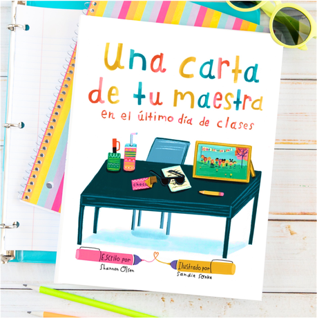 A colorful book cover titled Una carta de tu maestra en el último día de clases shows a classroom desk with supplies and a chalkboard. The book lies on lined notebooks with sunglasses nearby.