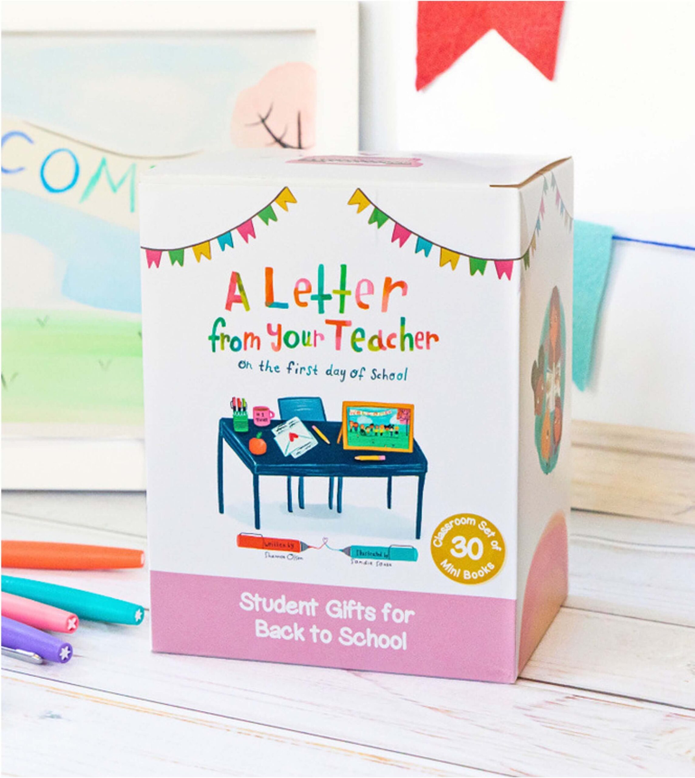 A colorful box labeled A Letter from Your Teacher on the First Day of School with an illustration of a teacher’s desk and supplies. The box advertises student gifts for back to school and includes 30 mini books.