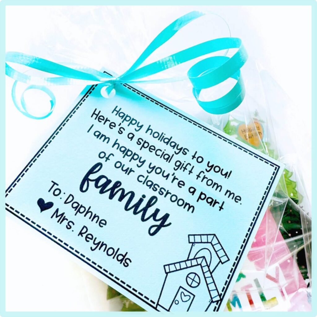 A gift tag with blue ribbon reads: Happy holidays to you! Heres a special gift from me. I am happy youre part of our classroom family. To: Daphne, Mrs. Reynolds with a birdhouse and heart illustration.