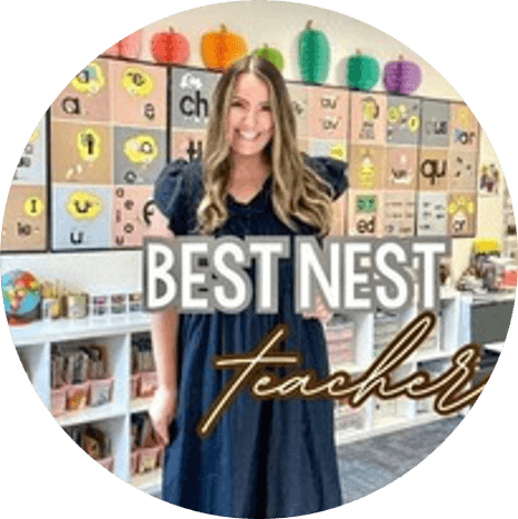 A smiling woman in a classroom stands in front of a decorated bulletin board with colorful letters and paper pumpkins. Text on the image reads Best Nest Teacher..